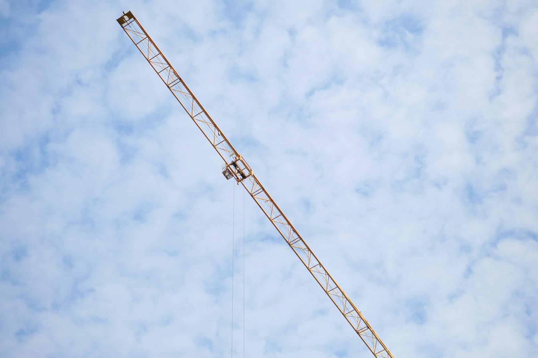 Wysoki żuraw budowlany na tle częściowo zachmurzonego nieba