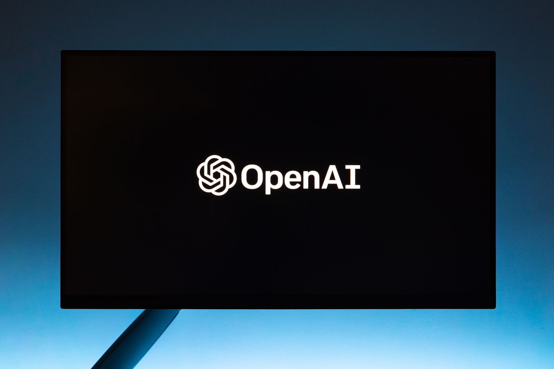 Logo OpenAI na minimalistycznym niebieskim ekranie