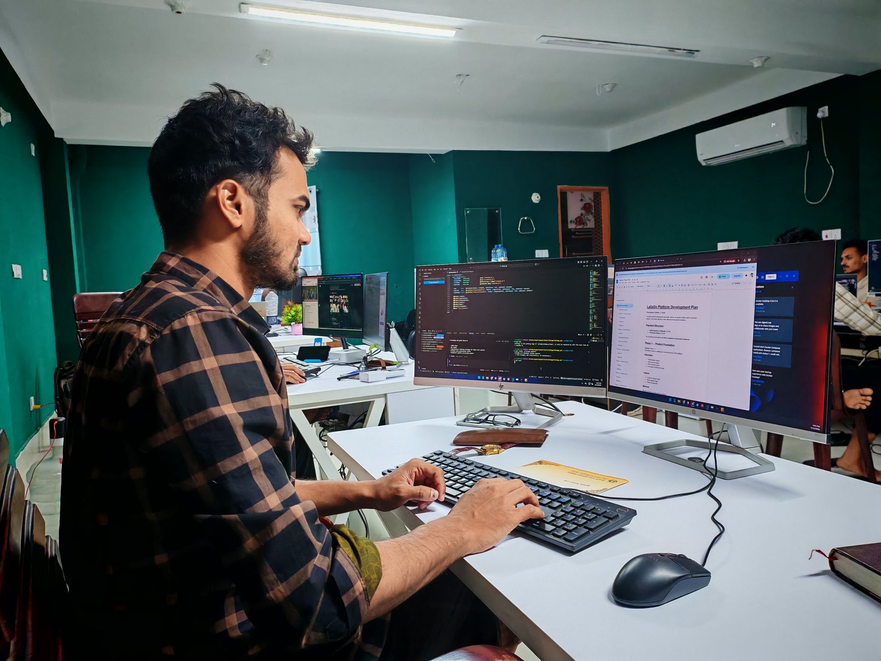Programista pracujący nad kodem PHP na dwóch monitorach w biurze Programista pracujący nad kodem PHP na dwóch monitorach w biurze